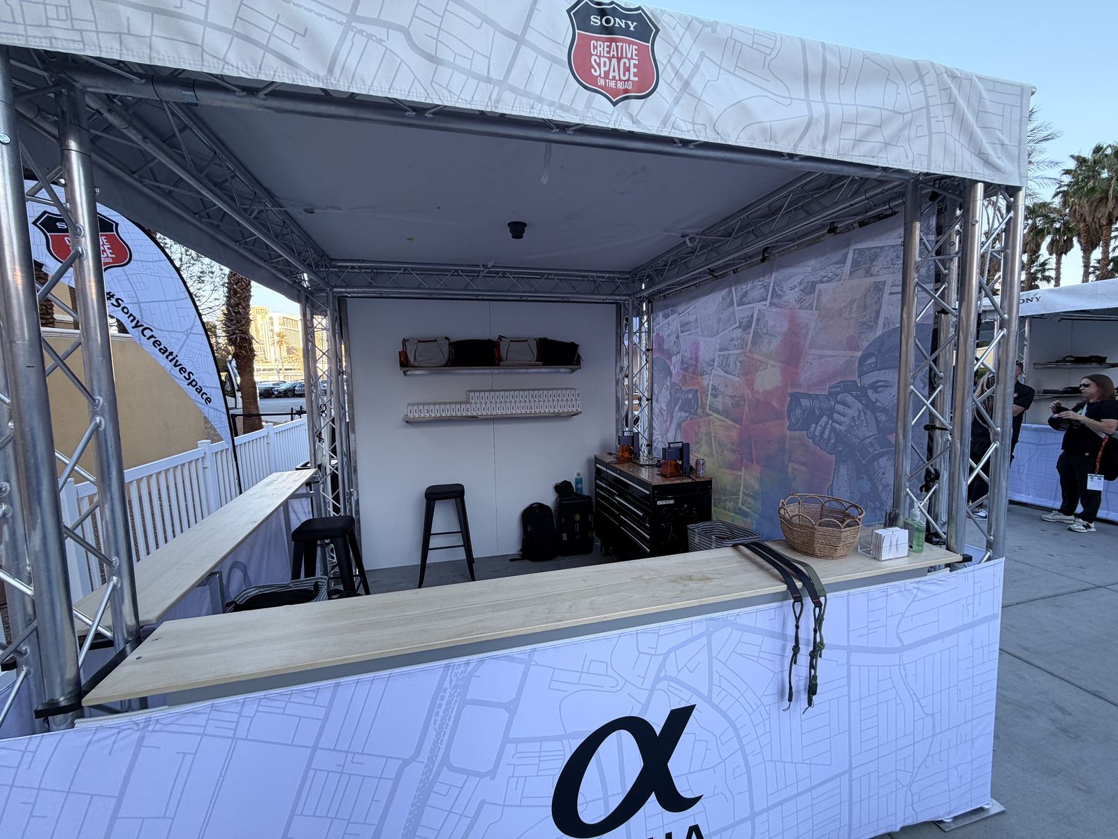 Fully branded truss booth built for an outdoor sponsor activation with counter and display shelving