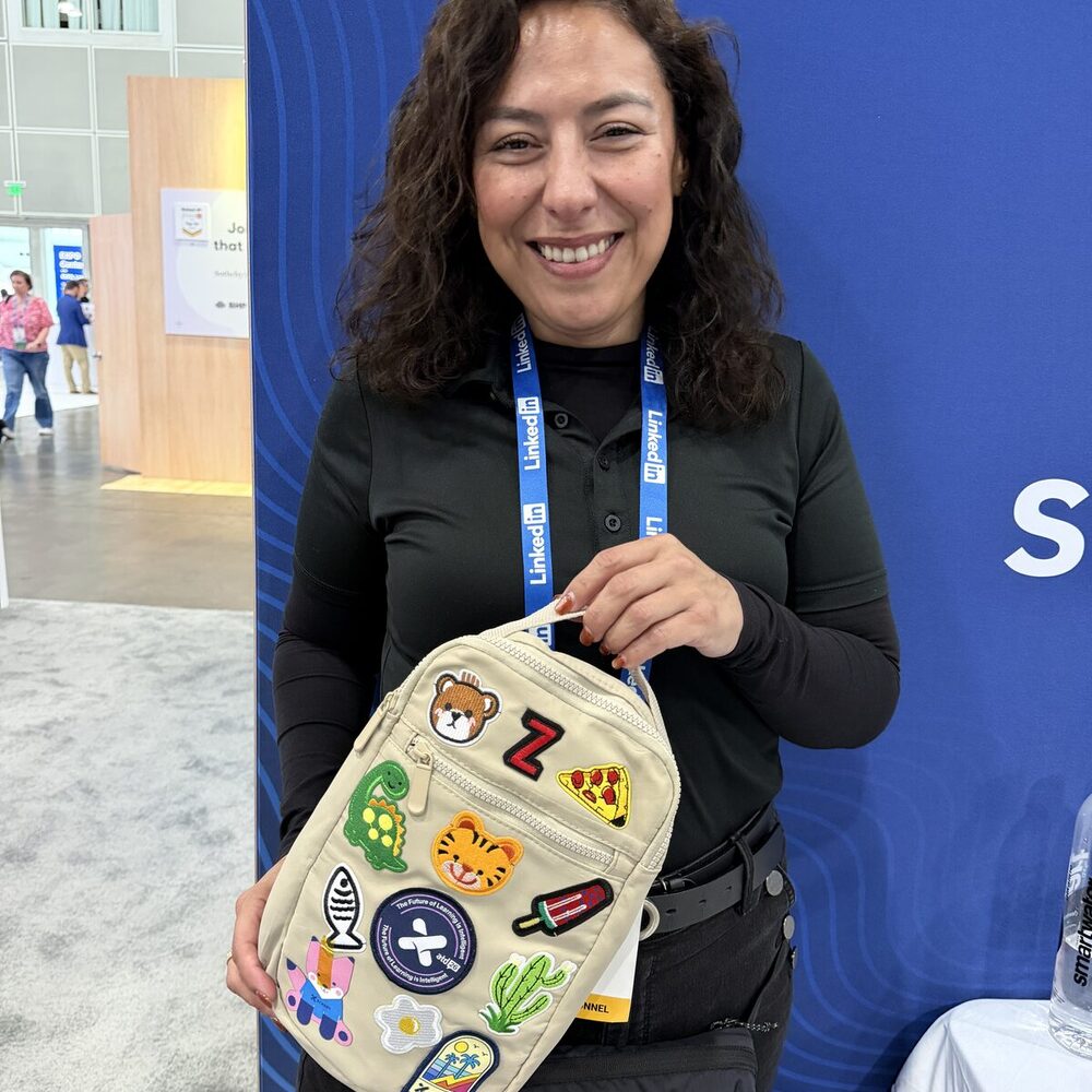 Smiling conference attendee holding a canvas bag customized with a colorful spread of heat-pressed patches