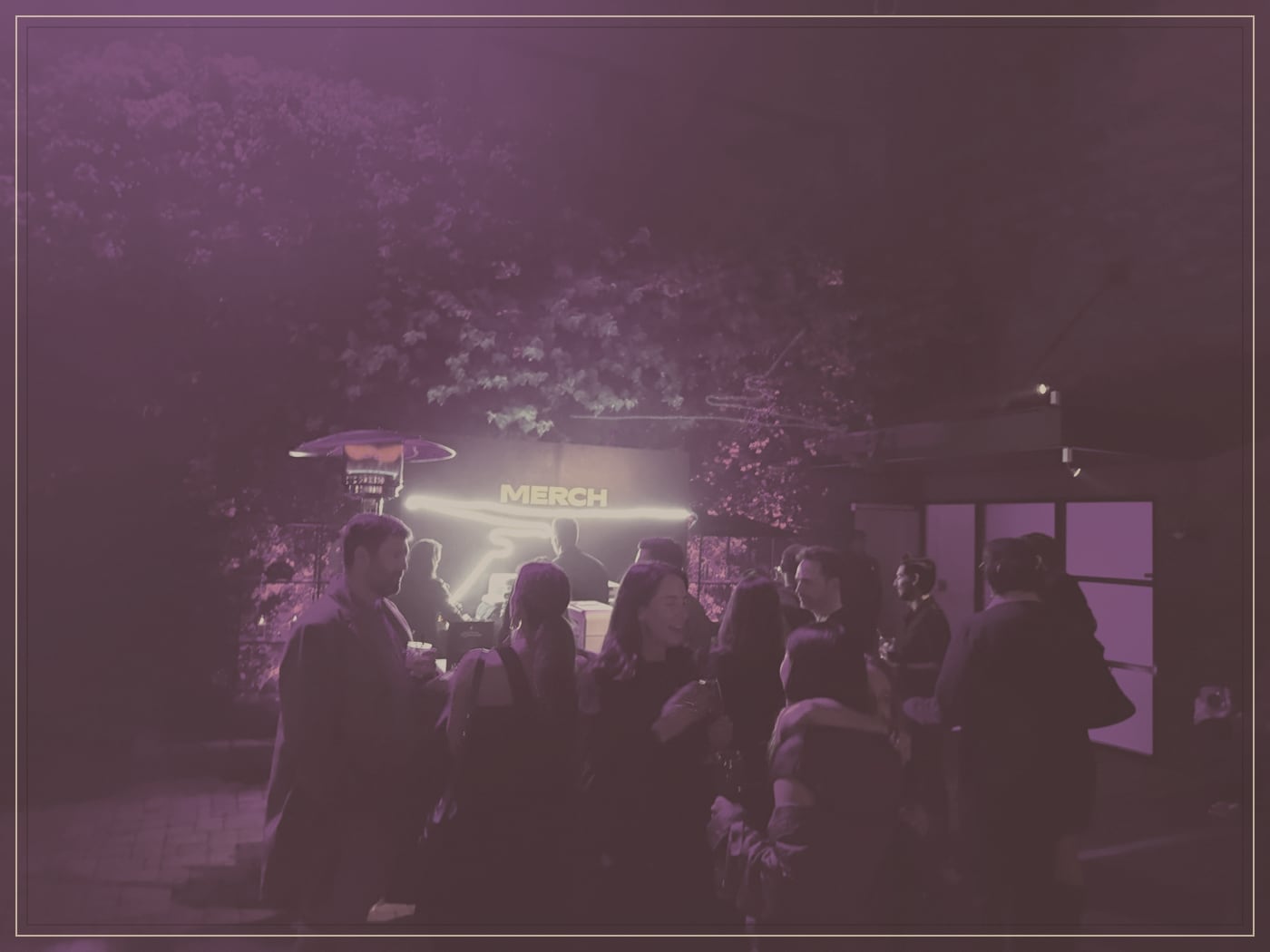 Guests gathered around a glowing booth in a garden courtyard at night