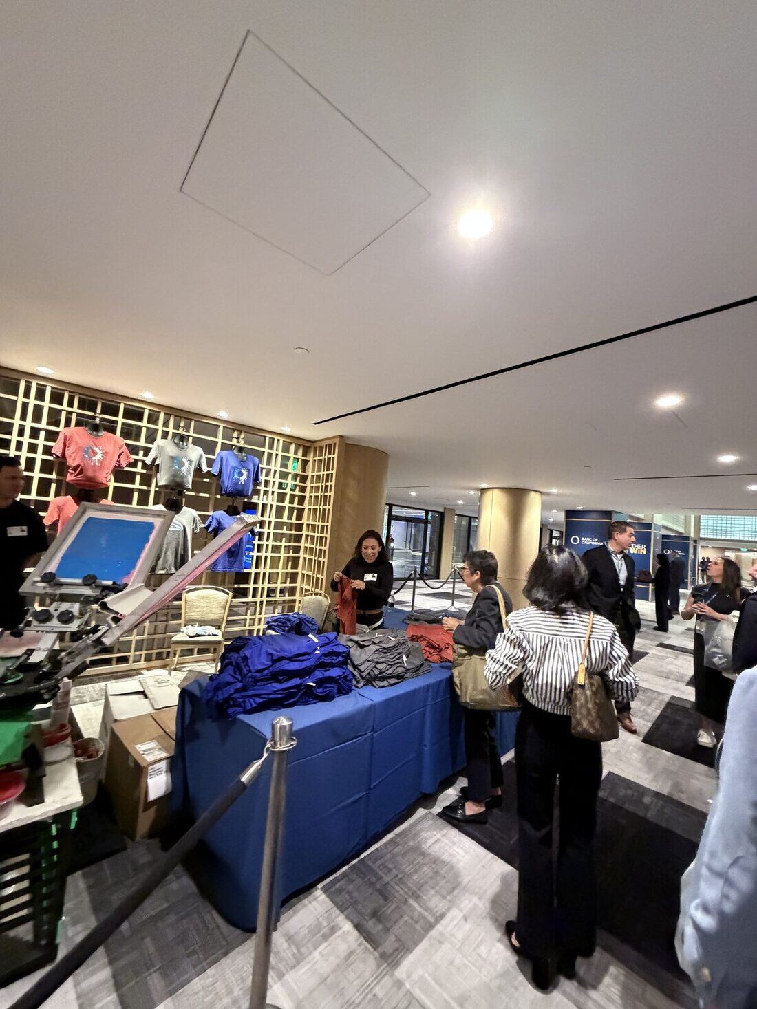 Employees waiting at a stanchioned customization line inside an office building lobby